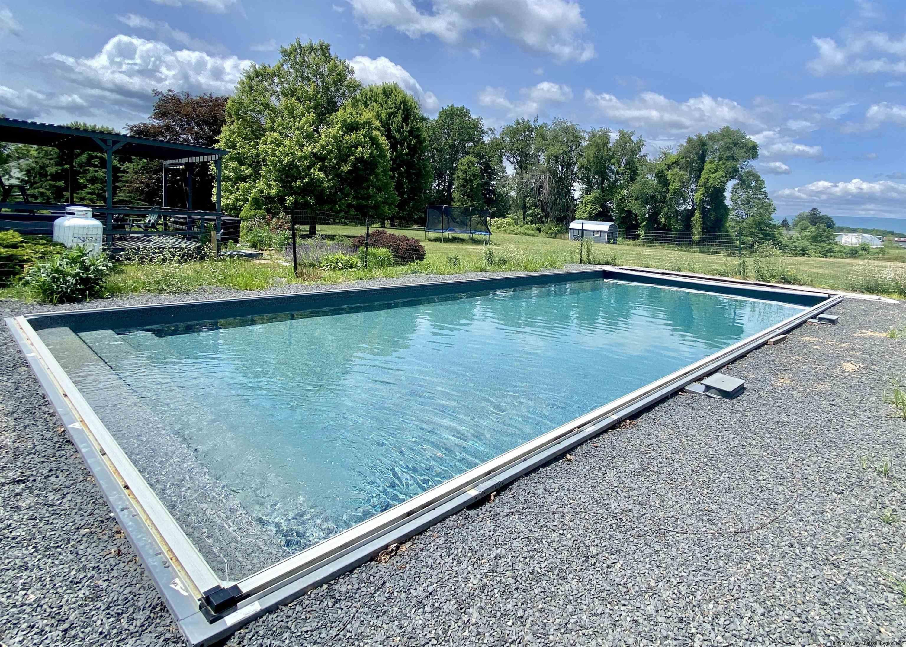 29 Millbrook Road Gardiner, NY 12589 - Photo 24 of 34 a view of a swimming pool with a bench and trees in the background