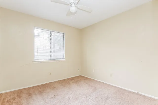 an empty room with a window and a ceiling fan