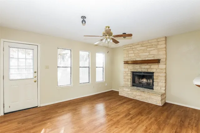 a view of empty room with wooden floor and fireplace