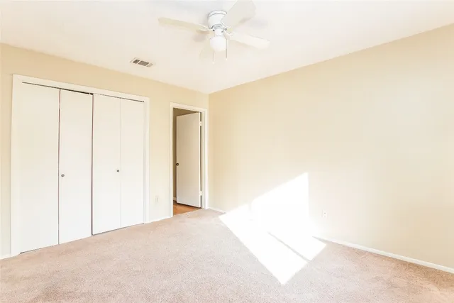 an empty room with a window and a ceiling fan