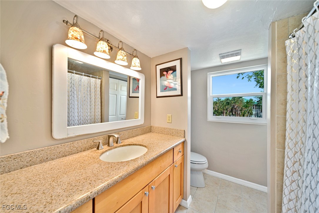 4546 Buck Key Road Sanibel, FL 33957 - Photo 22 of 41 a bathroom with a granite countertop sink mirror vanity and a toilet