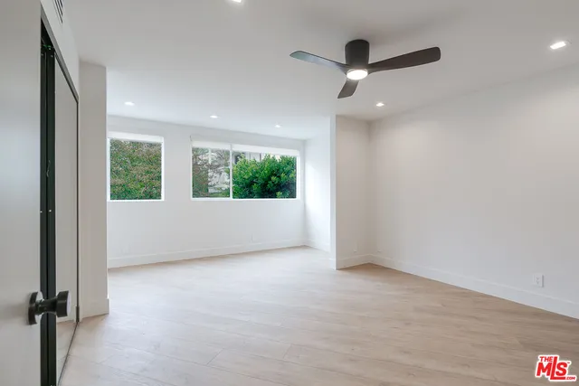 an empty room with windows and ceiling fan