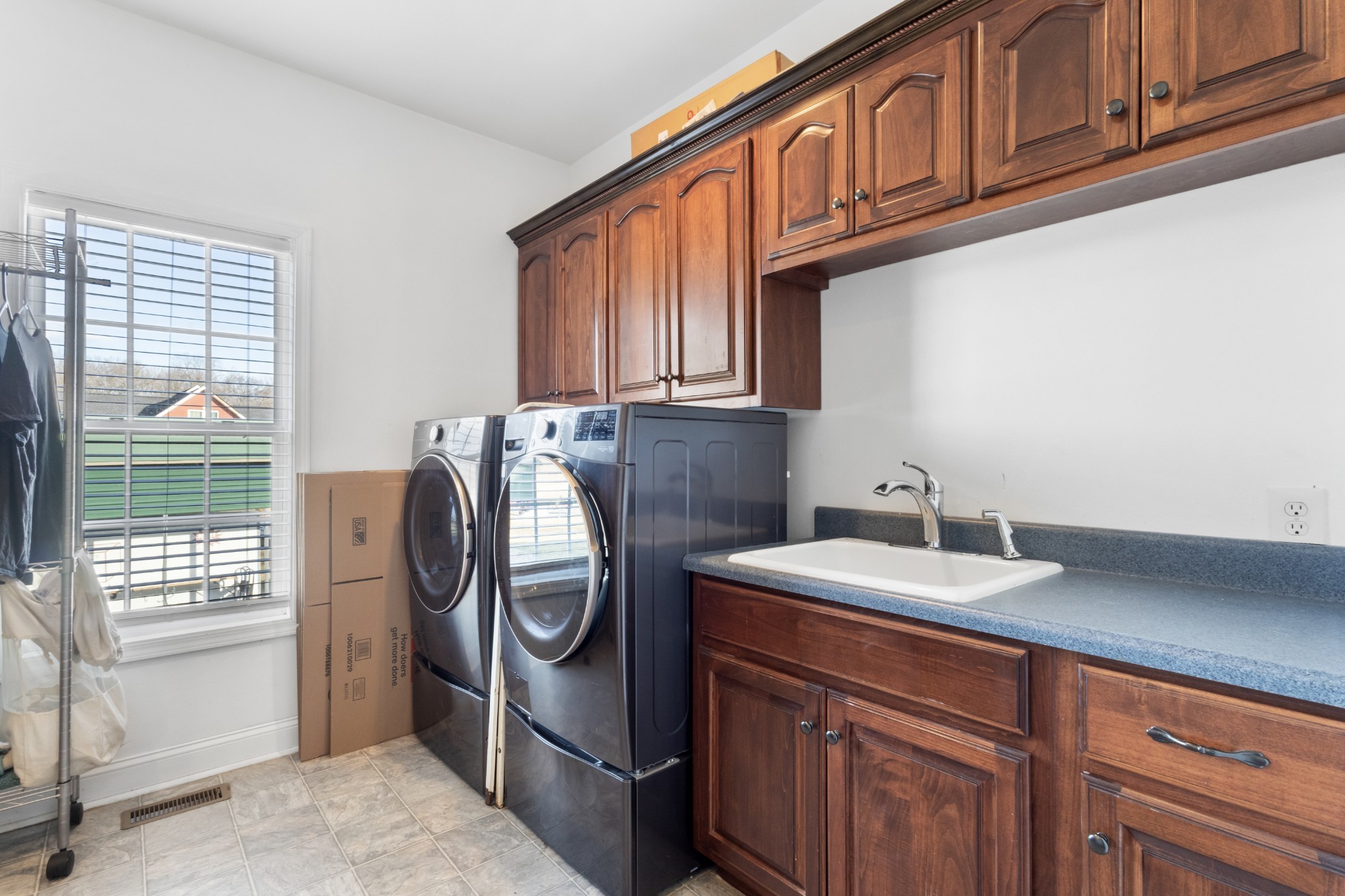 4591 Pineywoods Road Adams, TN 37010 - Photo 22 of 83 a utility room with stainless steel appliances granite countertop a sink a washer and dryer with wooden cabinets
