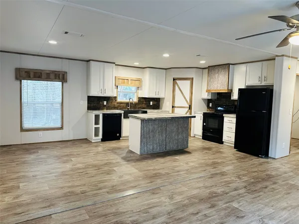 a kitchen with a dining table chairs appliances and a window