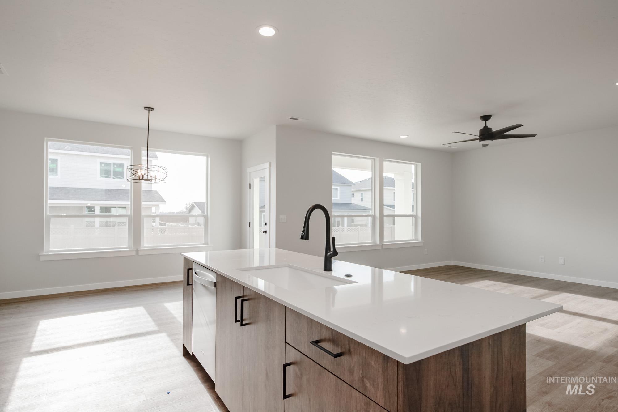 2135 South Border Way Meridian, ID 83642 - Photo 24 of 24 Kitchen featuring light wood finished floors, a kitchen island with sink, open floor plan, a ceiling fan, and wood finish cabinetry