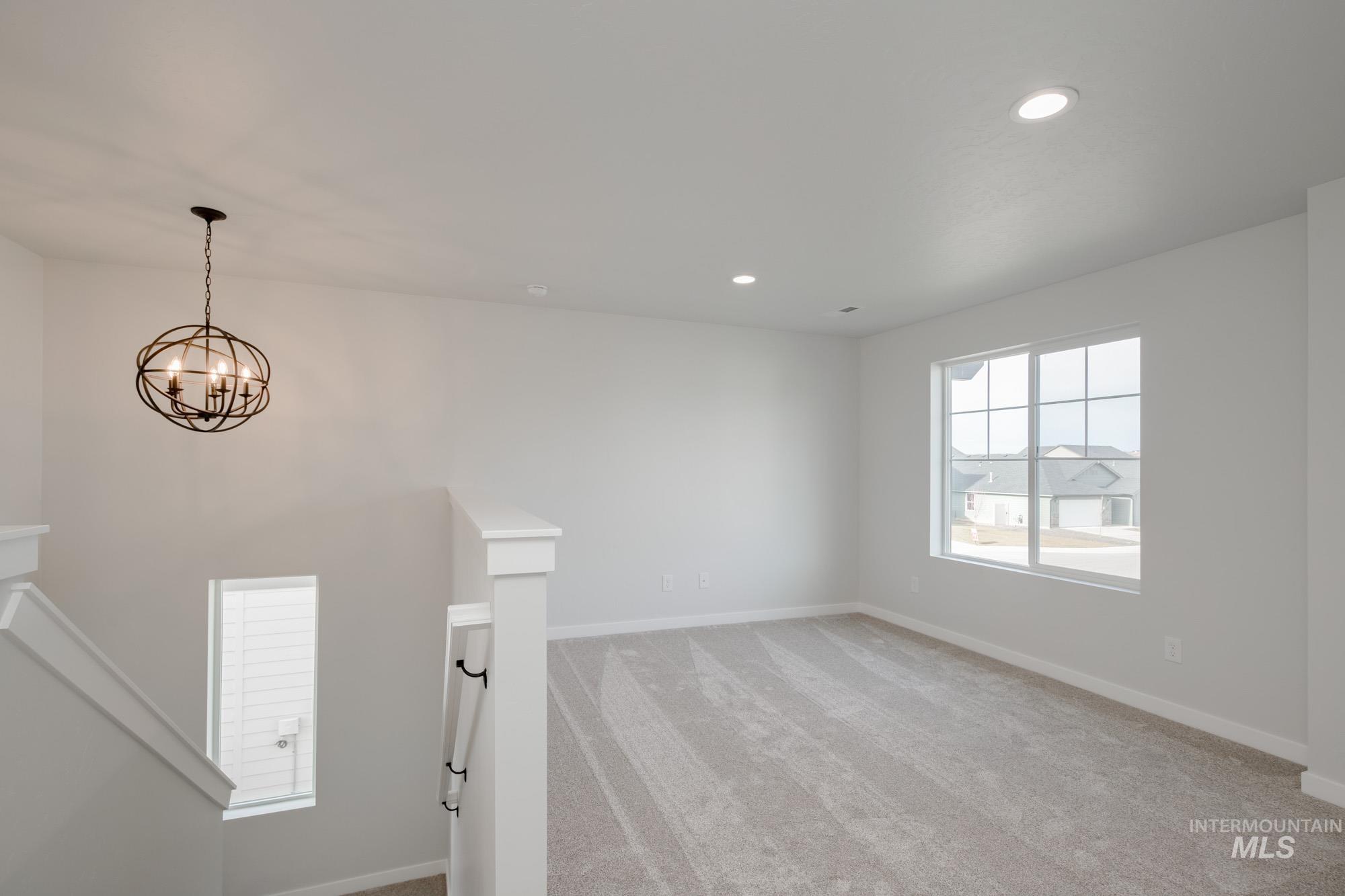 2135 South Border Way Meridian, ID 83642 - Photo 12 of 24 Empty room featuring light carpet and a chandelier