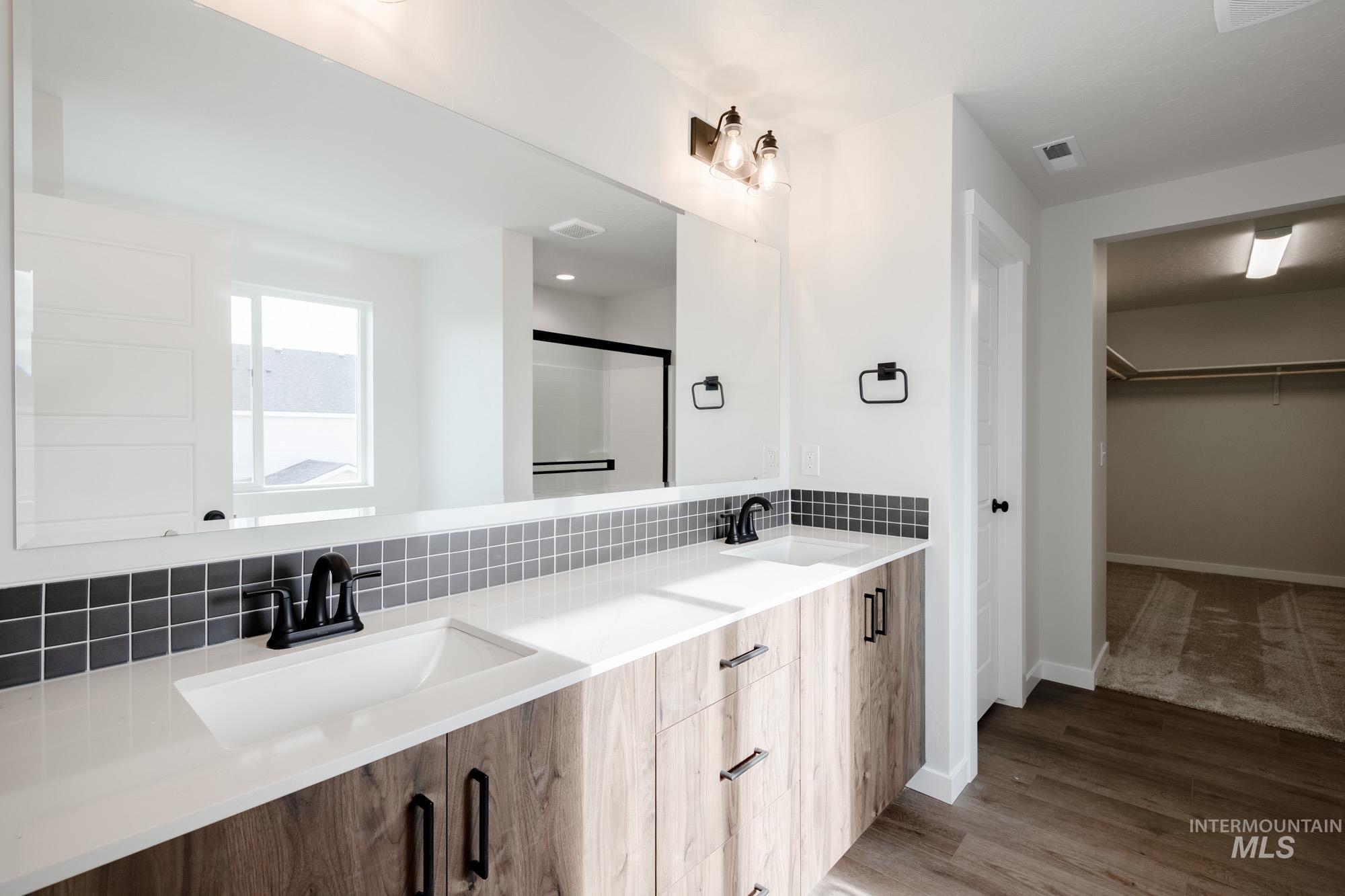 2135 South Border Way Meridian, ID 83642 - Photo 14 of 24 Bathroom featuring double vanity, a stall shower, a spacious closet, light wood-style floors, and tasteful backsplash