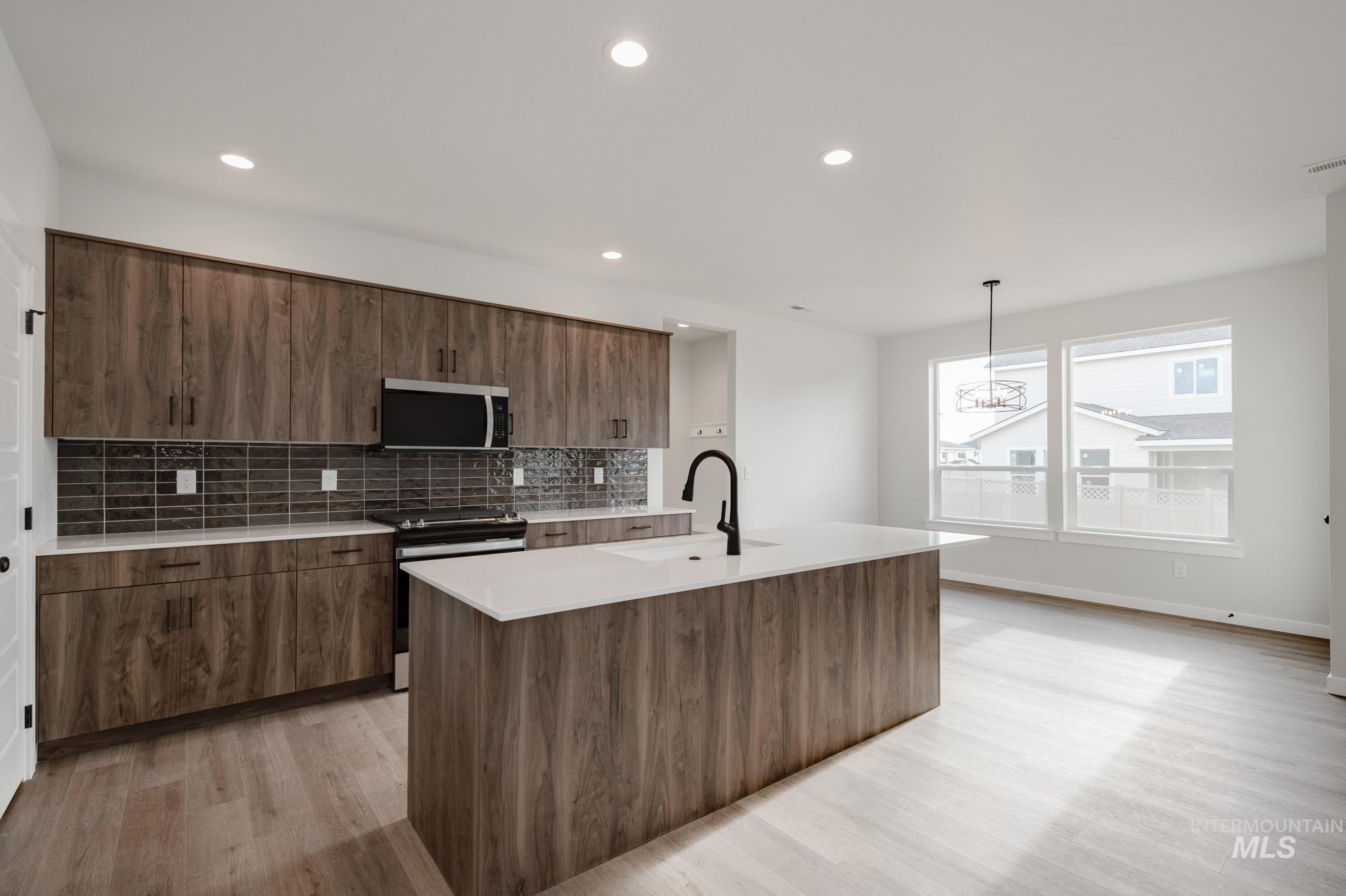 2135 South Border Way Meridian, ID 83642 - Photo 4 of 24 Kitchen featuring electric range, modern cabinets, a kitchen island with sink, stainless steel microwave, and light wood-style flooring