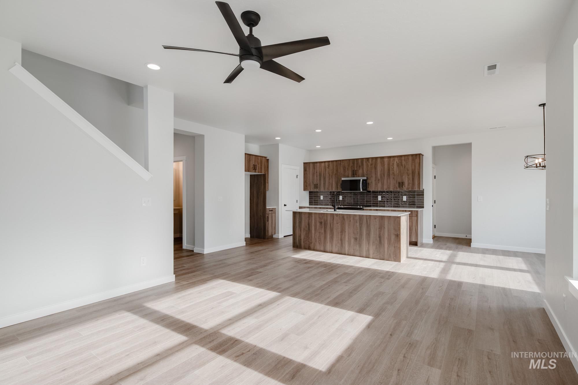 2135 South Border Way Meridian, ID 83642 - Photo 23 of 24 Kitchen featuring open floor plan, a ceiling fan, a center island with sink, light wood-style flooring, and stainless steel microwave