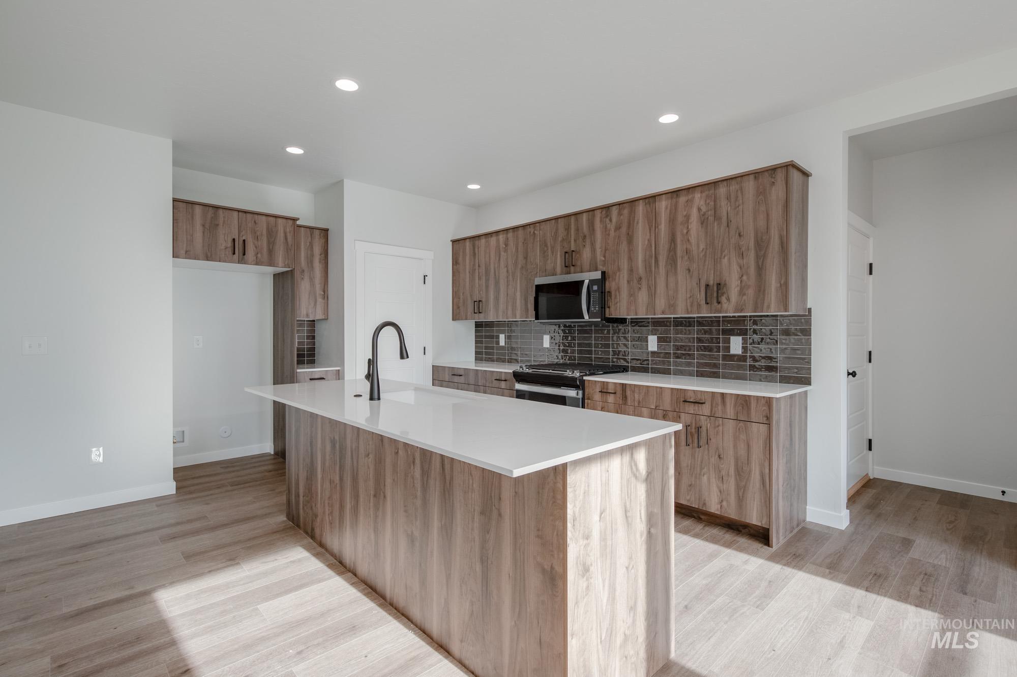 2135 South Border Way Meridian, ID 83642 - Photo 6 of 24 Kitchen featuring wood finish cabinetry, light wood-type flooring, tasteful backsplash, light stone counters, and recessed lighting