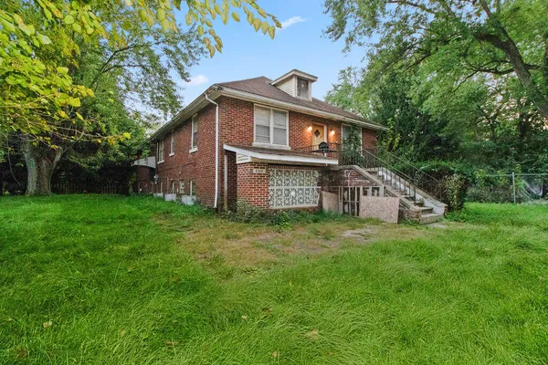 a view of a house with a big yard plants and large trees