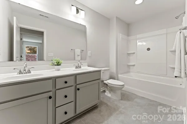 a bathroom with a double vanity sink toilet mirror and bathtub