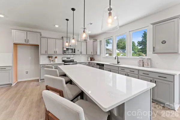 a large kitchen with cabinets a sink a center island stainless steel appliances and a window