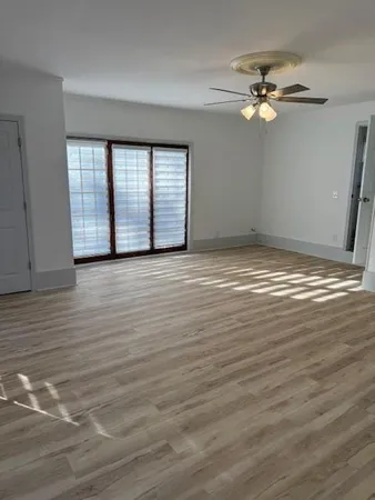 a view of an empty room with wooden floor and window
