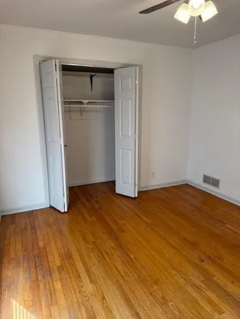 an empty room with wooden floor and chandelier fan