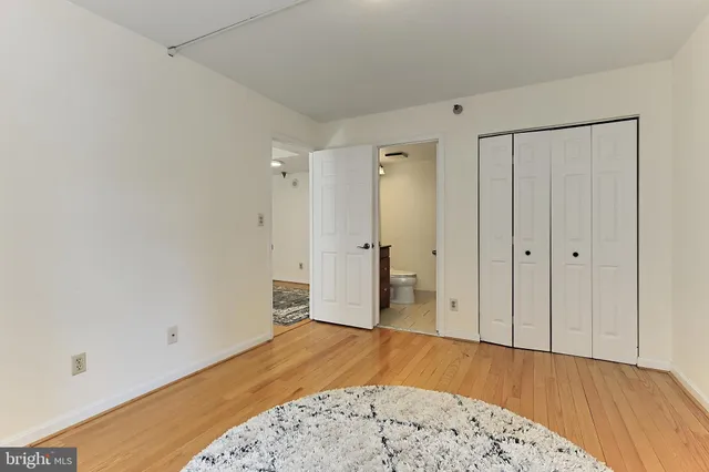 a view of a bedroom with wooden floor and a bathroom