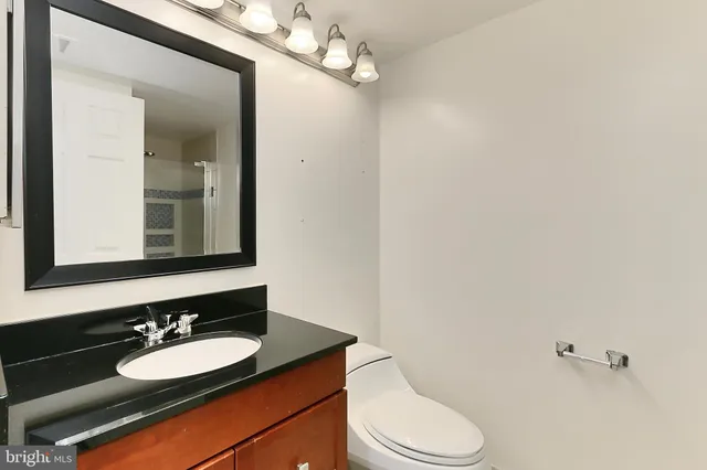 a bathroom with a granite countertop sink vanity mirror and toilet
