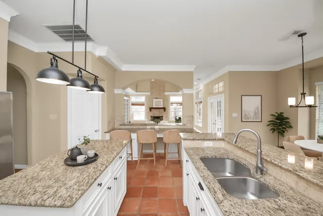 a spacious bedroom with a bed a chandelier and dresser