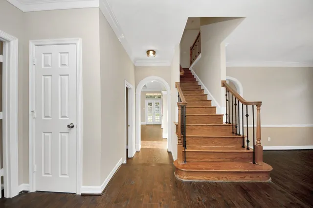 a view of a room with wooden floor stairs and a chandelier