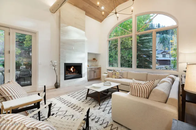 a living room with furniture fireplace and large windows