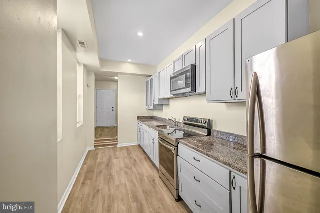 a kitchen with granite countertop a refrigerator stove top oven and sink