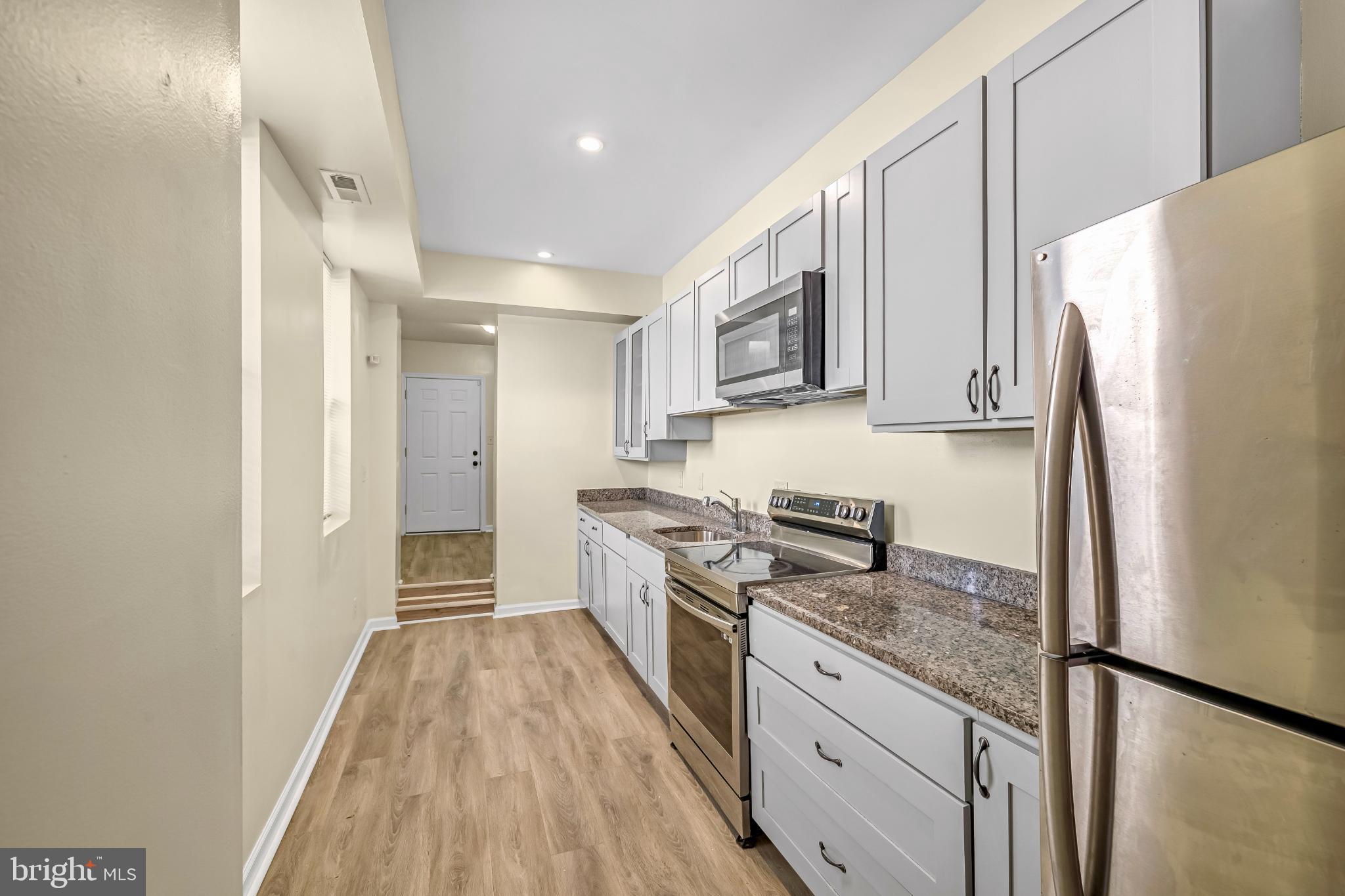 a kitchen with granite countertop a refrigerator stove top oven and sink