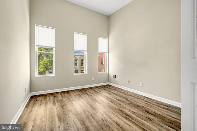 an empty room with wooden floor and windows