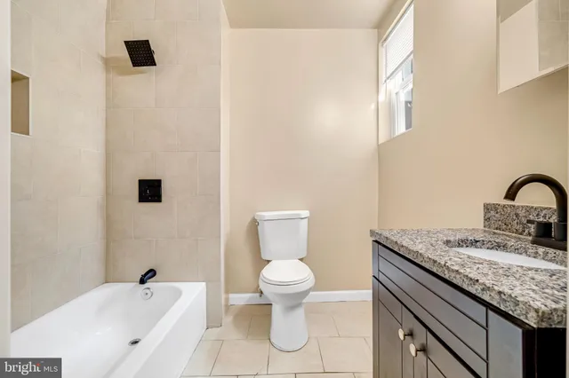 a bathroom with a granite countertop sink a toilet and a bathtub