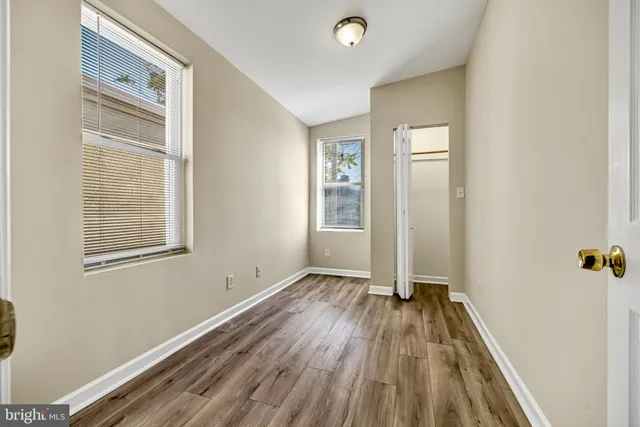 an empty room with wooden floor and windows