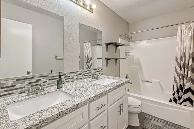 a bathroom with a granite countertop sink toilet and shower
