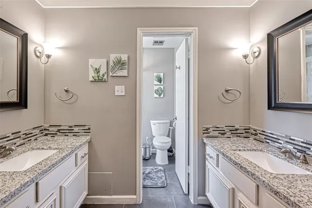 a bathroom with a granite countertop sink toilet and mirror