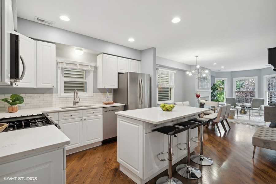 1219 West Melrose Street, Unit 2 Chicago, IL 60657 - Photo 8 of 13 a kitchen with stainless steel appliances granite countertop a stove a refrigerator a kitchen island a dining table and chairs