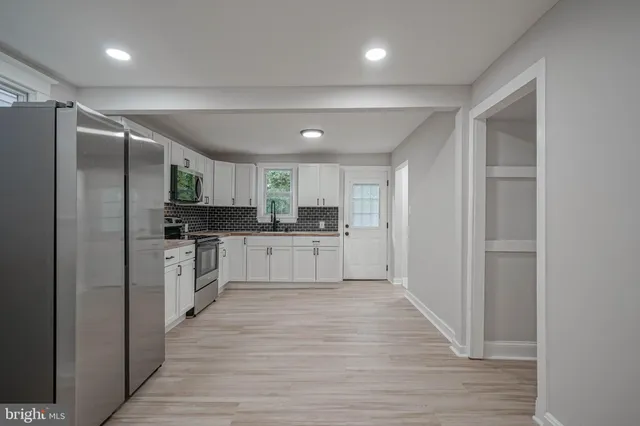 a large white kitchen with cabinets and wooden floor