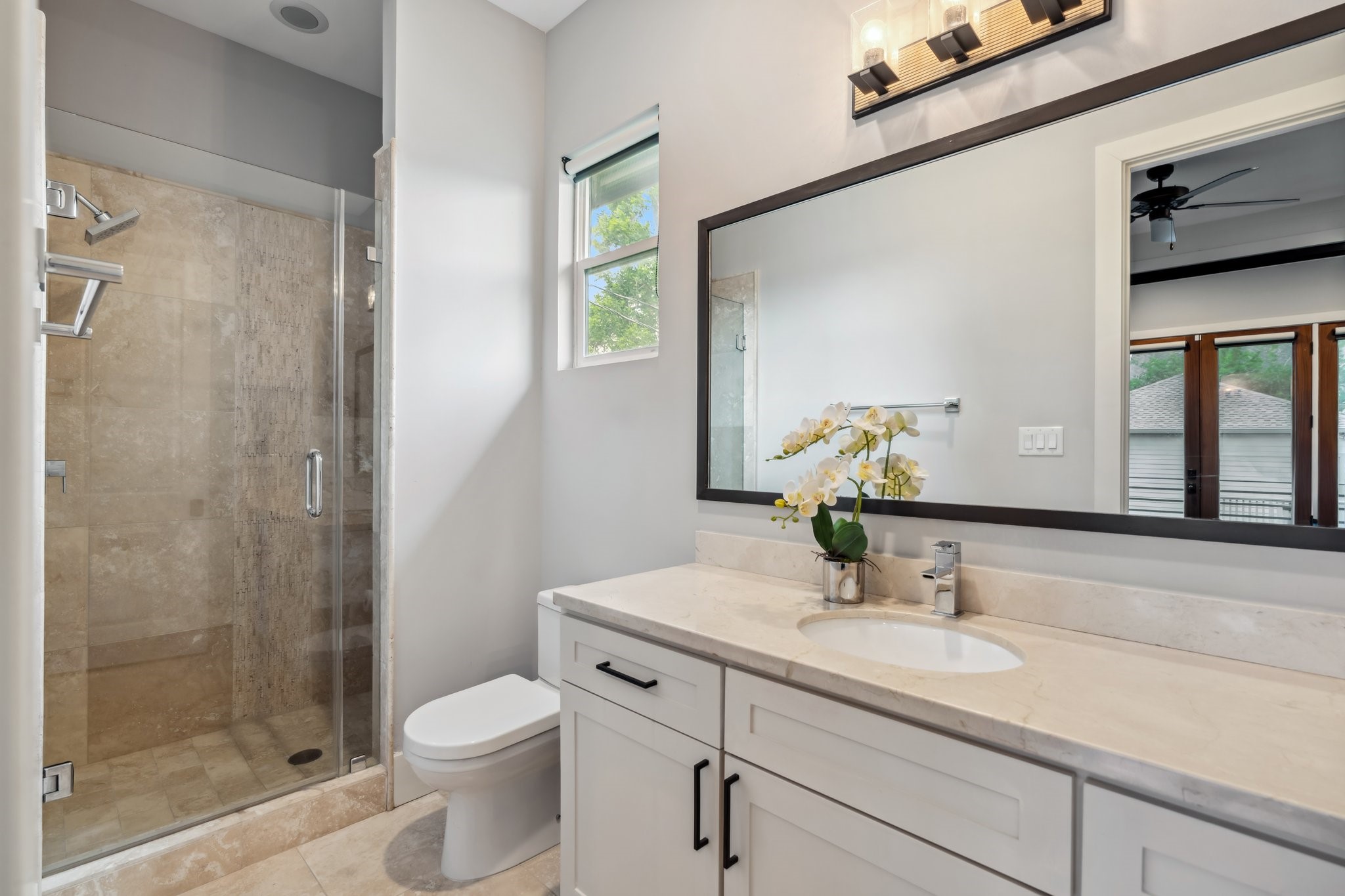 815 East 27th Street Houston, TX 77009 - Photo 30 of 44 The ensuite bathroom is both spacious and functional, with a large vanity offering ample storage, a decorative mirror, and vanity lights that provide soft illumination. The walk-in shower, complete with a glass door, offers a sleek and modern feel, making this bathroom as stylish as it is convenient.