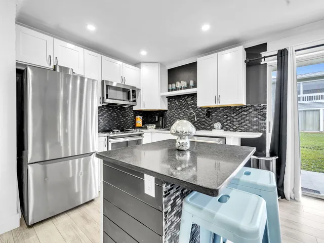 a kitchen with stainless steel appliances granite countertop a refrigerator a stove and a sink with wooden floor