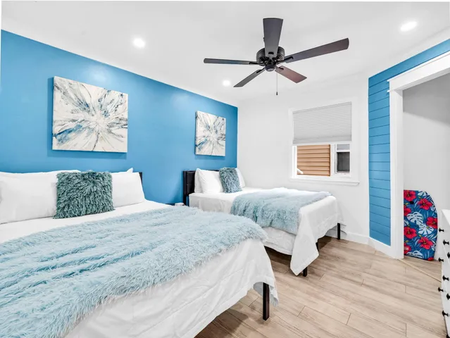 a bedroom with two beds and a ceiling fan