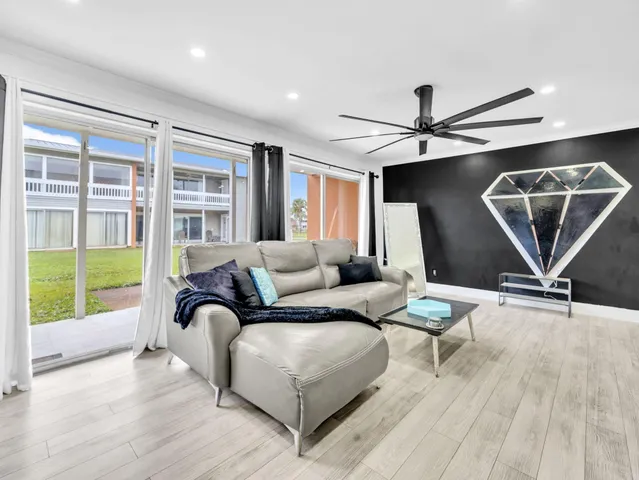a living room with furniture a ceiling fan and a wooden floor