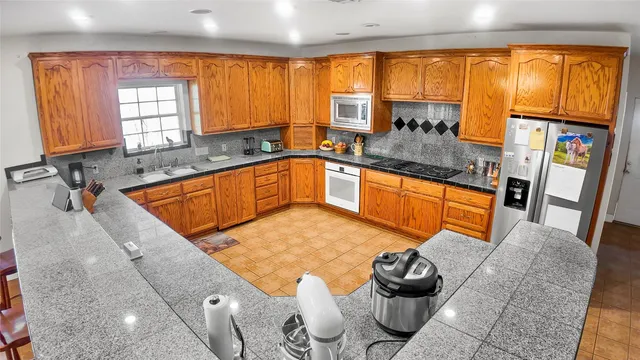 a kitchen with stainless steel appliances granite countertop a sink and a granite counter tops with a large window