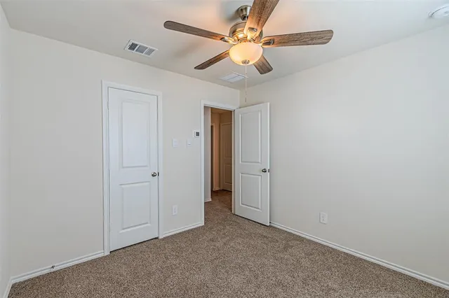 an empty room with closet and a ceiling fan