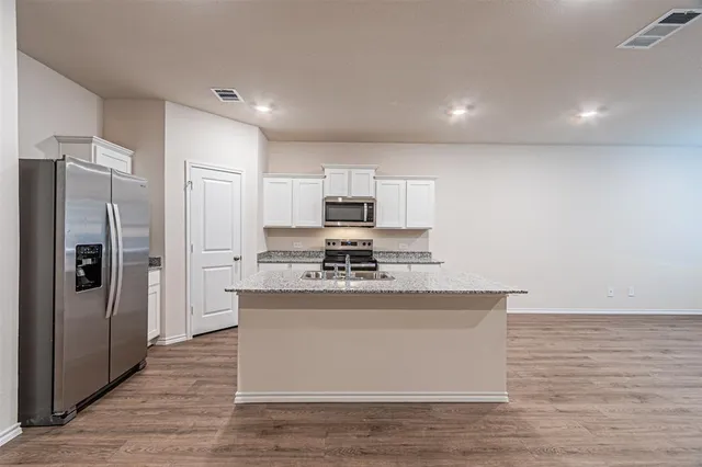 a large kitchen with stainless steel appliances granite countertop a stove a refrigerator and a microwave