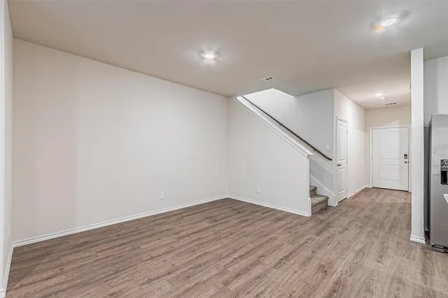 a view of an empty room with wooden floor and stairs