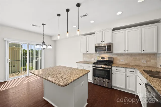 a large kitchen with kitchen island a stove a sink a center island and wooden floor