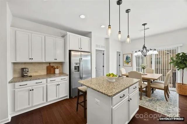 a kitchen with granite countertop kitchen island wooden cabinets and refrigerator