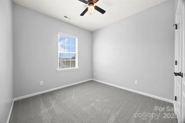 an empty room with ceiling fan and window