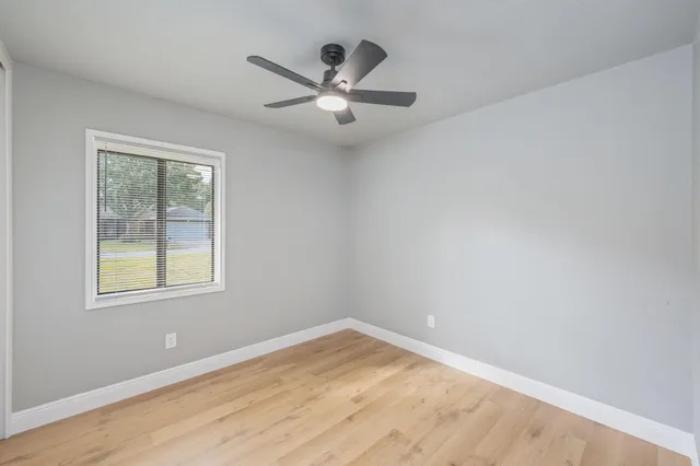 an empty room with a window and ceiling fan