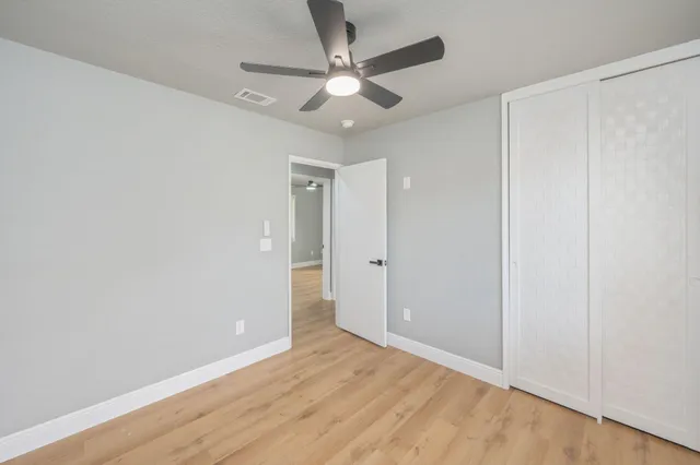 an empty room with wooden floor and ceiling fan