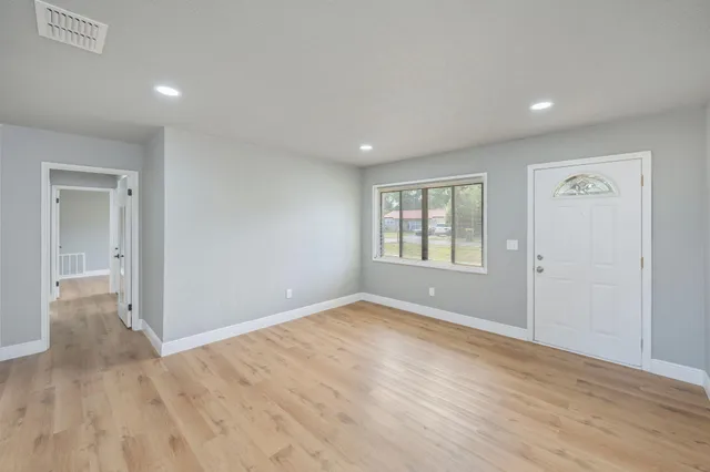a view of an empty room with wooden floor and a window