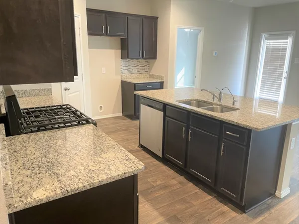 a kitchen with granite countertop a sink stove and cabinets