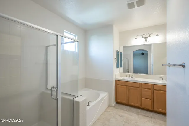 a bathroom with a double vanity sink a large mirror and a bathtub