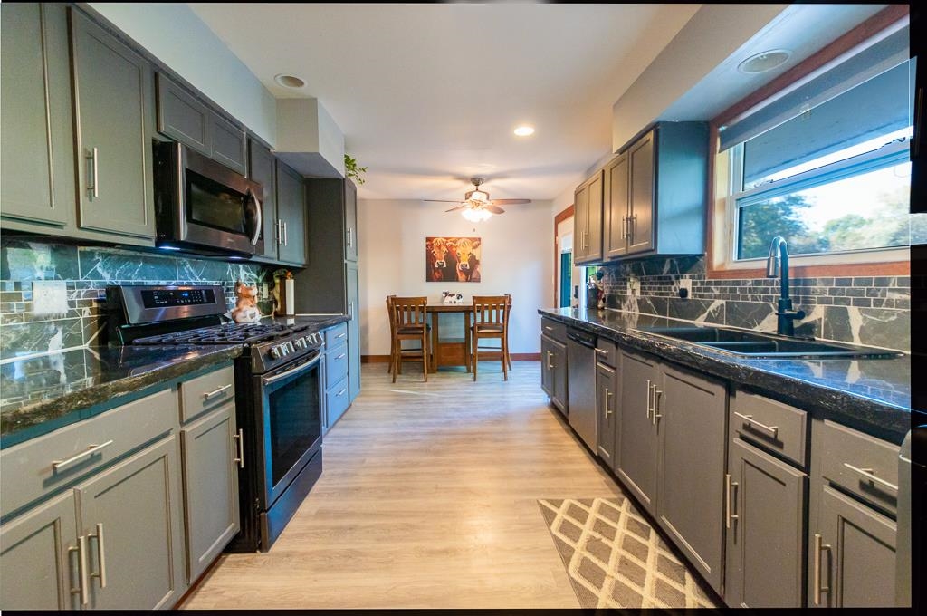 1045 North 2nd Street Rochelle, IL 61068 - Photo 13 of 15 a large kitchen with stainless steel appliances granite countertop a stove top oven a sink dishwasher a dining table and chairs with wooden floor